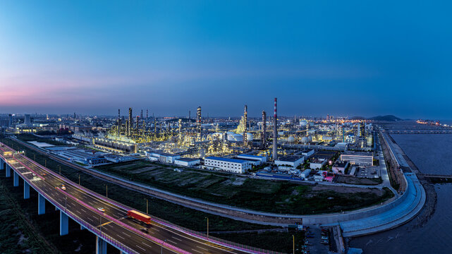 Aerial view of large petrochemical refinery and industrial park with highway traffic at dusk, illustrating energy infrastructure and manufacturing power.