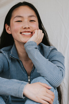 Portrait of smiling young woman sitting while leaning on elbow