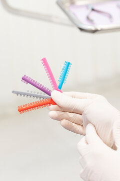 Dentist hand holding colorful orthodontic elastic ligatures