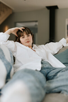 Portrait of confident young woman posing while sitting on sofa at home