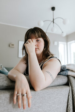 Portrait of young woman sitting on sofa in living room at home