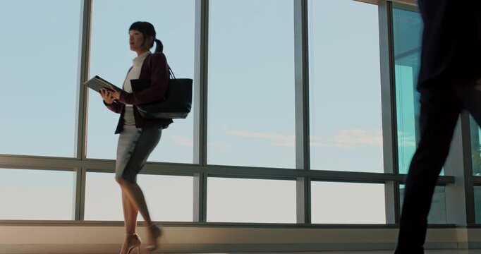 Walking, folder and woman in office hallway, corporate professional and travel for end of work day. Below, departure and business people with evening commute at workplace, complete tasks and leaving