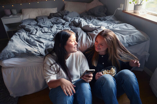 Happy girls spending leisure time sitting in bedroom at home