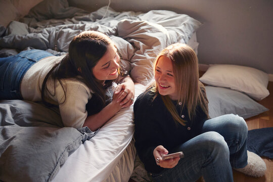 High angle view of happy girls talking to each other in attic at home
