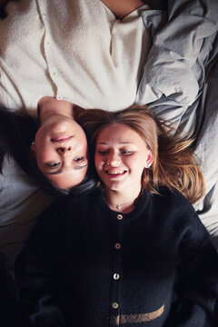 Directly above shot of multiracial girls spending leisure time lying on bed at home