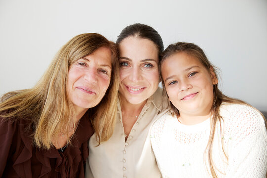 Portrait of smiling girl posing with her mother and aunt at home