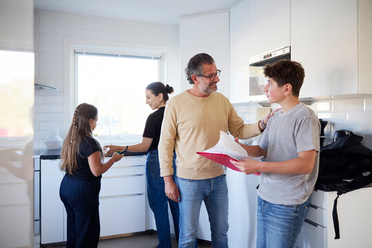 Smiling man congratulating his son for passing exams at home