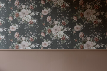 Chic wainscotted room interior with vintage moody dark grey floral wallpaper featuring pale pink and cream peonies and roses above a smooth, warm terracotta-pink painted wall panel with a matching cha © Francis