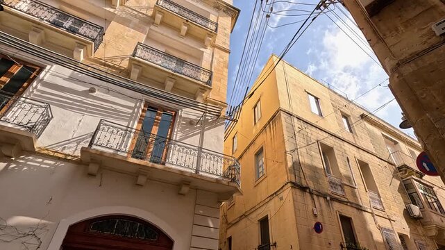 Сozy old street in Valletta viewed from below looking upward, bathed in sunlight on a clear day
