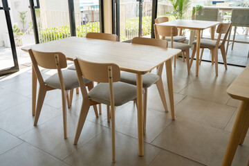Fototapeta premium Modern minimalist cafe interior with wooden tables and chairs. Bright airy restaurant dining area with Scandinavian furniture design overlooking the sea. Ideal for lifestyle and decor.