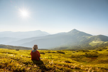 Fototapeta premium Female tourist gazing on summer mountains glowing by golden evening sunlight. Carpathian mountains. Landscape photography