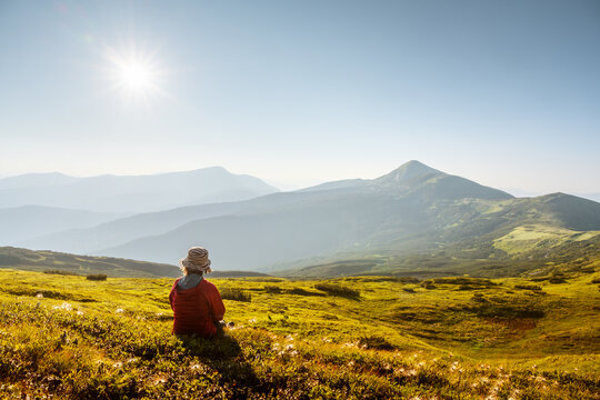 Female tourist gazing on summer mountains glowing by golden evening sunlight. Carpathian mountains. Landscape photography