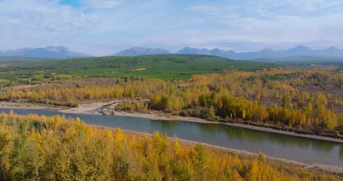 Aerial dolly to river with golden autumn forest and mountain valley rural Montana, drone backdrop