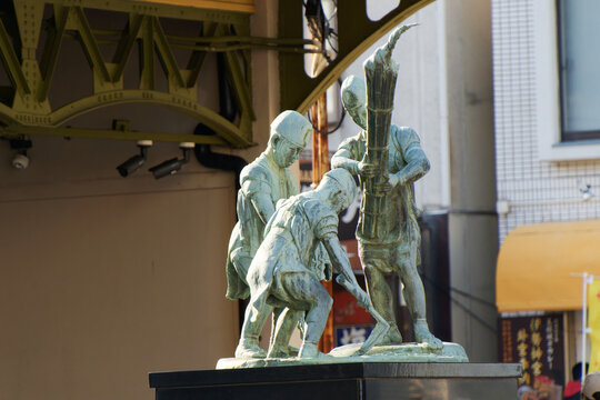 Bronze statue of traditional harbor workers at Mojiko port historical site under sunlight in Japan.