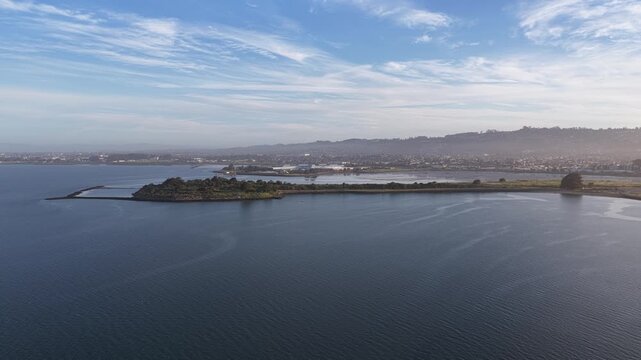 Aerial drone footage revealing a panoramic view of the Albany Bulb taken from Cesar Chavez Park in Berkeley, California, with the serene waters of the San Francisco Bay under a vast blue sky
