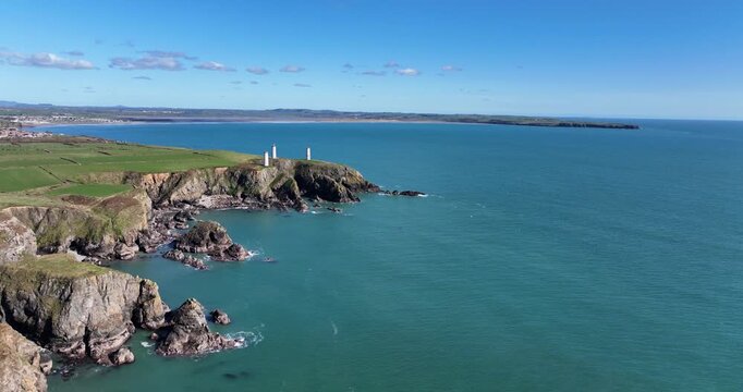 drone flying along slowly Metalman towers at the entrance to Tramore Bay Waterford Ireland and Brownstown Head in background pillars navigation ares to shipping in days gone by bright spring morning