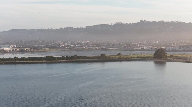 Morning aerial view from a drone flying over the bay, revealing the Albany waterfront with the Berkeley hills in the background on a hazy day