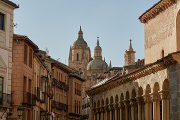 Fototapeta premium Charming street scene in the historic center of Segovia with traditional architecture, arcaded buildings, and a view of the iconic Segovia Cathedral rising above the rooftops. 