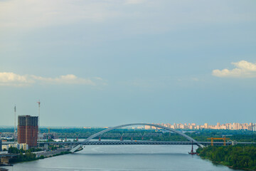 Obraz premium Aerial view of a wide river flowing through an Eastern European city with bridges and industrial elements