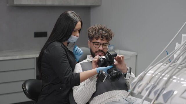 Dentist shows patient dental treatment process with camera in a modern clinic setting