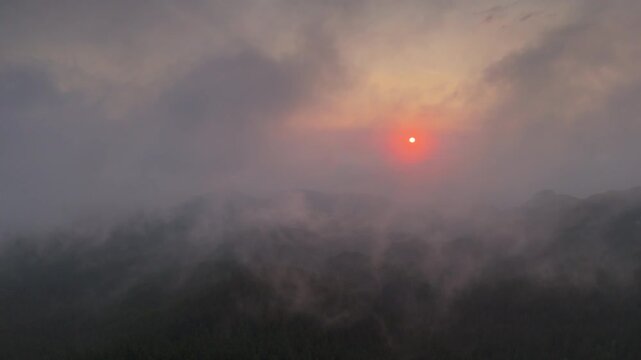 Majestic Aerial Pull Back Above Moody Mountain Ranges at Stunning Sunrise with Fast Moving Clouds