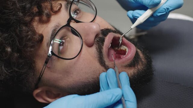 Close up of dentist examining patient front teeth using dental mirror