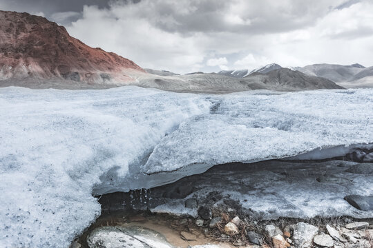 Disintegration of the snow layer in the mountains by a river and stream, water flowing and snow melting in the highlands of the Tien Shan in the Pamirs of Tajikistan