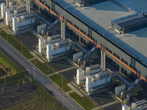 Aerial view of data center building showcasing infrastructure and multiple external cooling units in an industrial area, representing internet ai communication, Middenmeer, Netherlands.