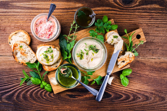 Masala swirl joghurt dip, cannellini white bean spread, salsa verde, marinades and snack for grill party with bread and herbs served as top view on a wooden board
