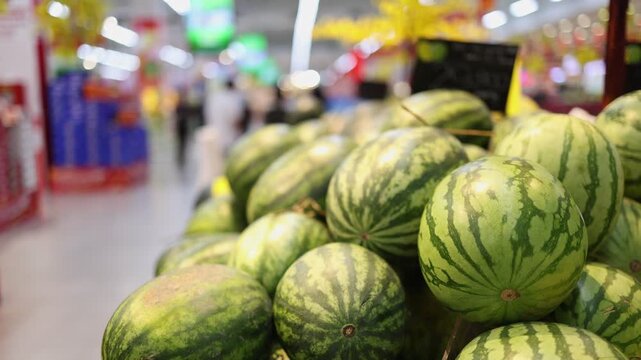 Close up of fresh striped watermelons on a shelf in a supermarket. Pile of organic ripe fruit in a grocery store. Healthy nutrition and natural sweet snack concept for summer diet.