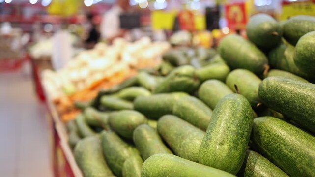 Close up of fresh winter melon in a grocery store. Variety of organic wax gourd vegetables piled on a supermarket shelf. Healthy nutrition and natural ingredient concept for cooking and food market.