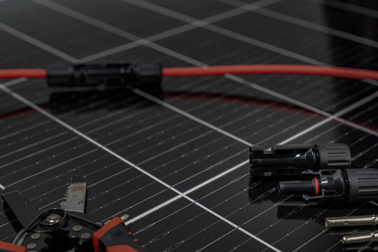 Solar panel connector cable and MC4 plug installation tools on photovoltaic surface