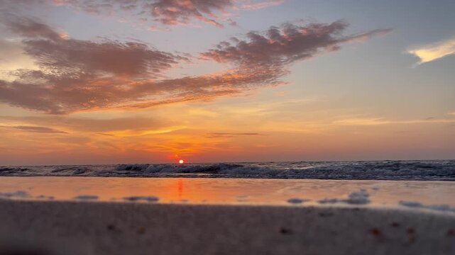 Serene Sunset Over The Ocean With Dramatic Clouds and Reflective Waves