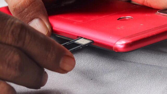 Close-up of male hands inserting, removing and replacing sim card from mobile phone, demonstrating process of changing cellular provider or managing mobile data.