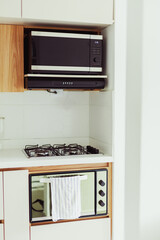 Fototapeta premium Modern kitchen with built-in microwave, gas stove and oven in compact interior layout, home appliance and cooking concept