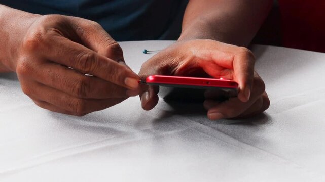 Close-up of male hands inserting, removing and replacing sim card from mobile phone, demonstrating process of changing cellular provider or managing mobile data.