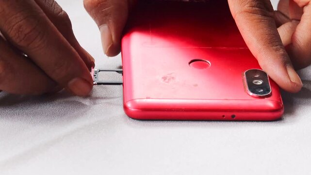 Close-up of male hands inserting, removing and replacing sim card from mobile phone, demonstrating process of changing cellular provider or managing mobile data.