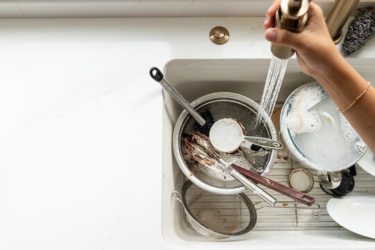 Overhead view of rinsing baking dishes in white farmhouse kitchen sink