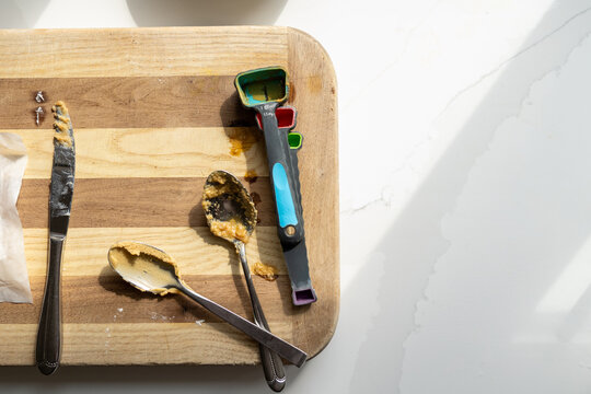 Dirty measuring spoons on wooden cutting board with marble counter copy space