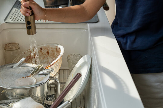 Person rinsing baking bowls at kitchen sink after making brownies
