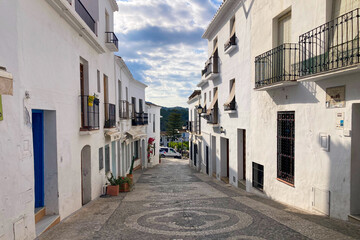 Fototapeta premium A peaceful walk through the charming narrow streets, surrounded by whitewashed houses and colorful flowers in Frigiliana, Spain
