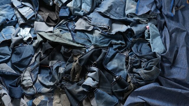 Pile of denim fabric scraps left after clothing production. Concept of textile waste, denim recycling, sustainable fashion and environmental responsibility