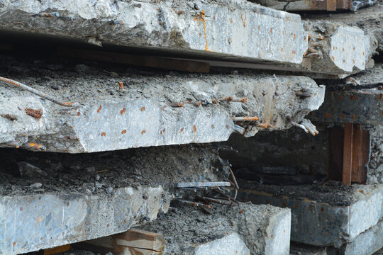 Stack of broken concrete beams with rusty iron rebar. Debris from demolition site. Industrial waste from building destruction. Raw material for recycling and construction site cleanup.