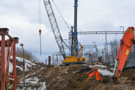 Yellow crane and orange excavator at road construction site. Heavy building machinery digging earth for infrastructure project. Industrial industry foundation development operation.