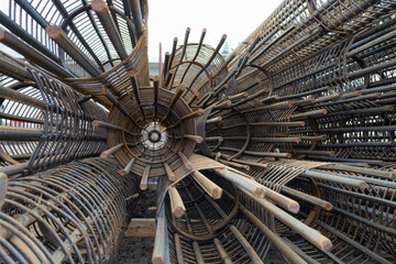 Steel reinforcement rebar cages stacked at construction site. Metal frames for concrete pile foundation. Industrial building material with geometric structure. Infrastructure project.