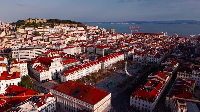 Aerial orbit shot of Rossio Square with Sao Jorge Castle and Lisbon rooftops at golden hour