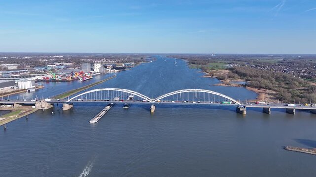 Bridge with dense highway traffic and cargo vessel on a wide river in Europe