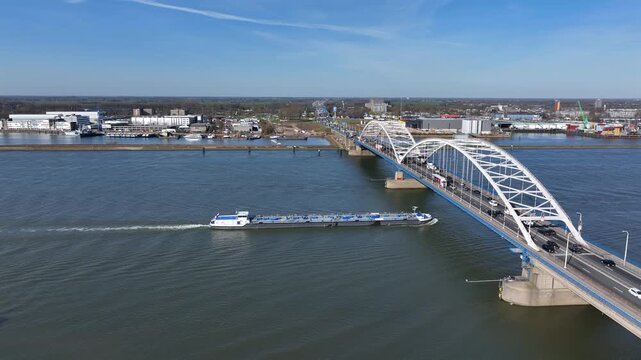 Bridge with dense highway traffic and cargo vessel on a wide river in Europe