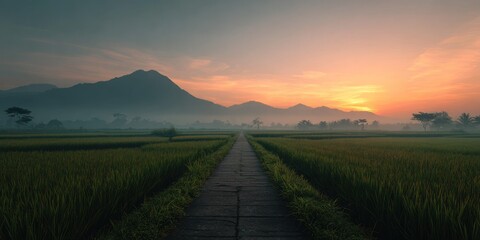 Naklejka premium Road leading through fields with mountains at sunrise with golden sky