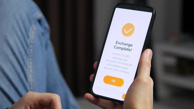 Converting BTC to US dollars on financial smartphone app. Selling digital assets on a mobile phone. User converts Bitcoin to fiat cash in a modern finance app. Screen shows processing and successful